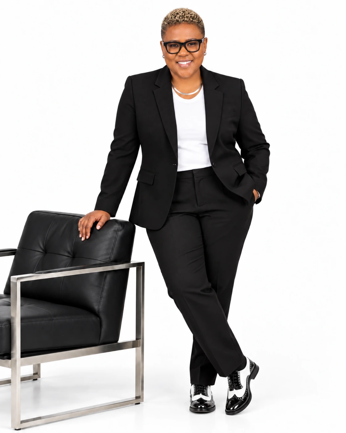 Rev. Dr. Elise Saulsberry standing in black suit beside chair